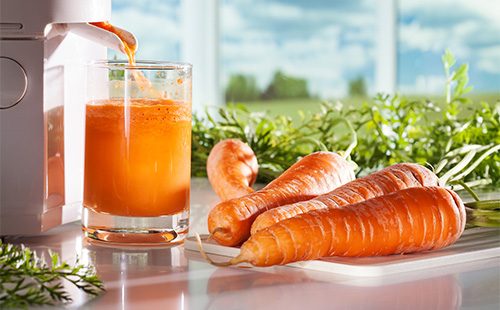 Морковный сок течет из соковыжималки