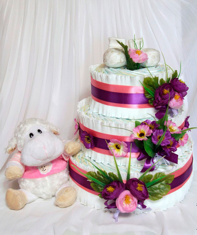 Украсить торт из памперсов можно лентами, цветами, одеждой для новорожденного