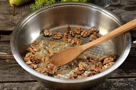 Добавить в горячую сковороду 1 столовую ложку мёда и быстро перемешать. Все орехи должны со всех сторон покрыться мёдом. Прогреть орехи в меду приблизительно 1 минуту.